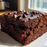 A close-up, moist slice of rich chocolate Banana Bread Brownies topped with melted chocolate chips.