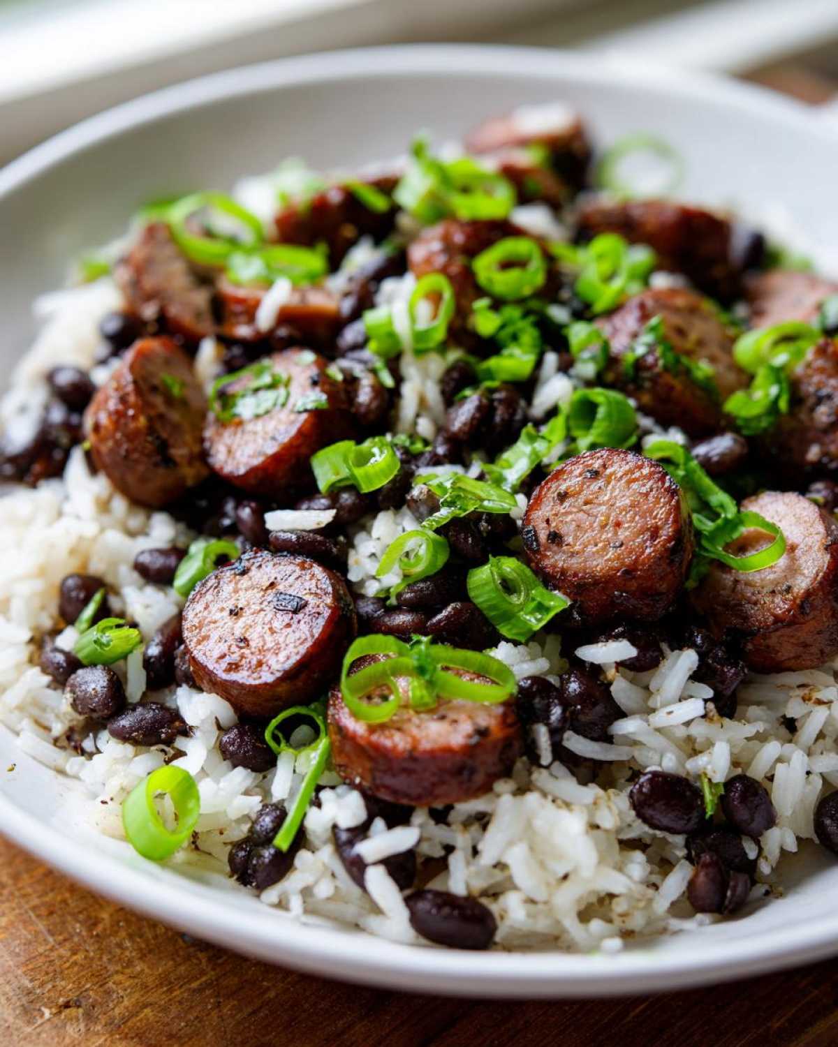 Close-up of One-Pot Black Beans and Rice with Sausage topped with sliced green onions.
