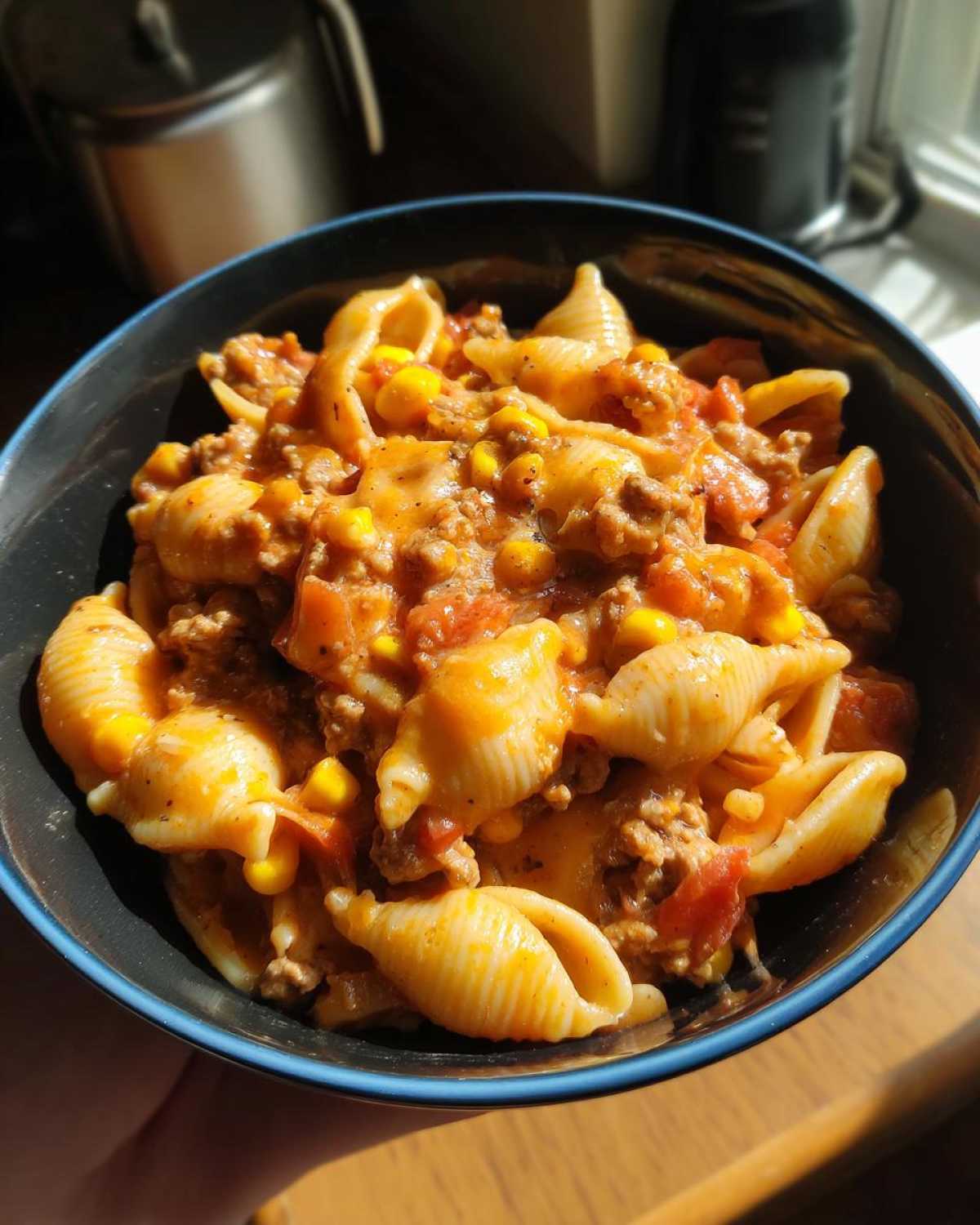 A close-up overhead view of a bowl filled with creamy One Pot Taco Pasta featuring shell pasta, ground meat, tomatoes, and corn.