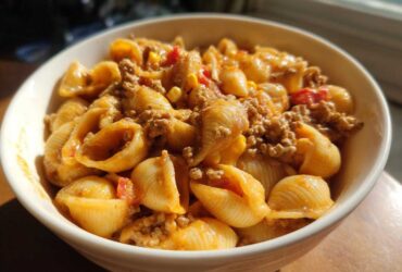 Close-up of a creamy bowl of One Pot Taco Pasta featuring shell pasta, seasoned ground meat, and corn.