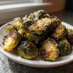 A close-up of crispy, caramelized Oven Roasted Brussels Sprouts with Parmesan cheese sprinkled on top.