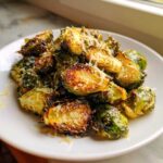 Crispy Oven Roasted Brussels Sprouts with Parmesan cheese sprinkled on top, served on a white plate.