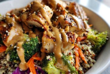 Close-up of a Protein Packed Thai Peanut Chicken Buddha Bowl with grilled chicken, broccoli, carrots, and peanut sauce over quinoa.
