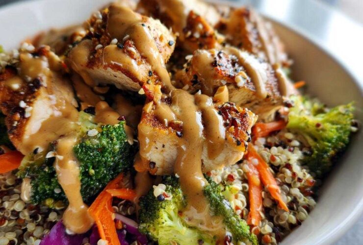 Close-up of a Protein Packed Thai Peanut Chicken Buddha Bowl with grilled chicken, broccoli, carrots, and peanut sauce over quinoa.
