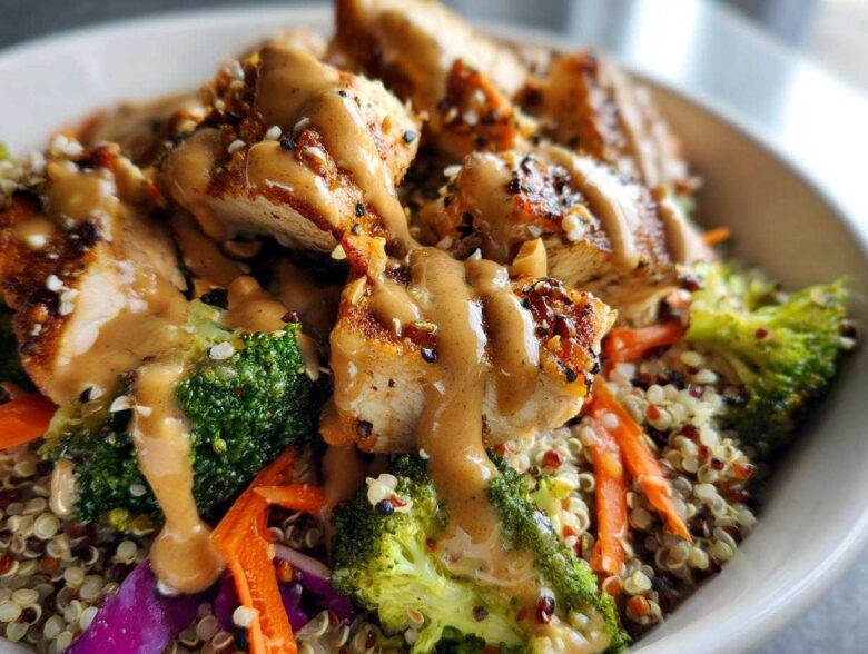 Close-up of a Protein Packed Thai Peanut Chicken Buddha Bowl with grilled chicken, broccoli, carrots, and peanut sauce over quinoa.