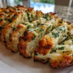 Close-up of freshly baked Sliced Garlic Bread with Cheese, showing melted cheese and green herbs.