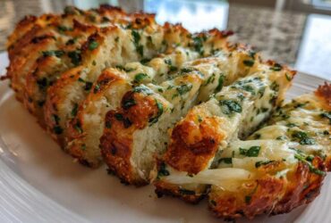 Close-up of freshly baked Sliced Garlic Bread with Cheese, showing melted cheese and green herbs.