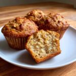 Close-up of moist Sourdough Discard Apple Muffins, one cut open showing apple chunks and nuts.
