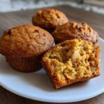 Close-up of moist Sourdough Discard Apple Muffins, one cut open showing apple chunks inside.