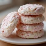 A stack of four soft, white Strawberry Shortcake Butter Cookies with pink flecks on a white plate.