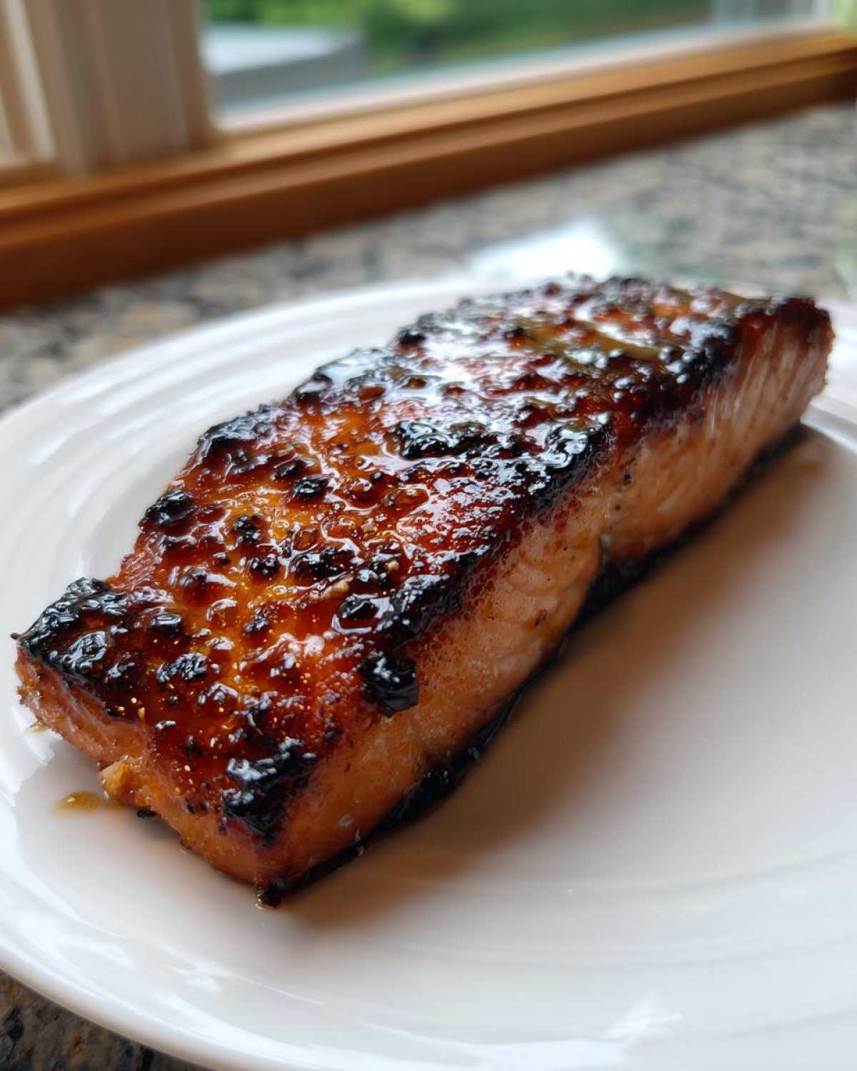 A perfectly cooked, glazed Texas Roadhouse Salmon fillet resting on a white plate.