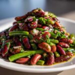 Close-up of a vibrant Bean Salad featuring kidney beans, green beans, red onion, and fresh herbs tossed in dressing.