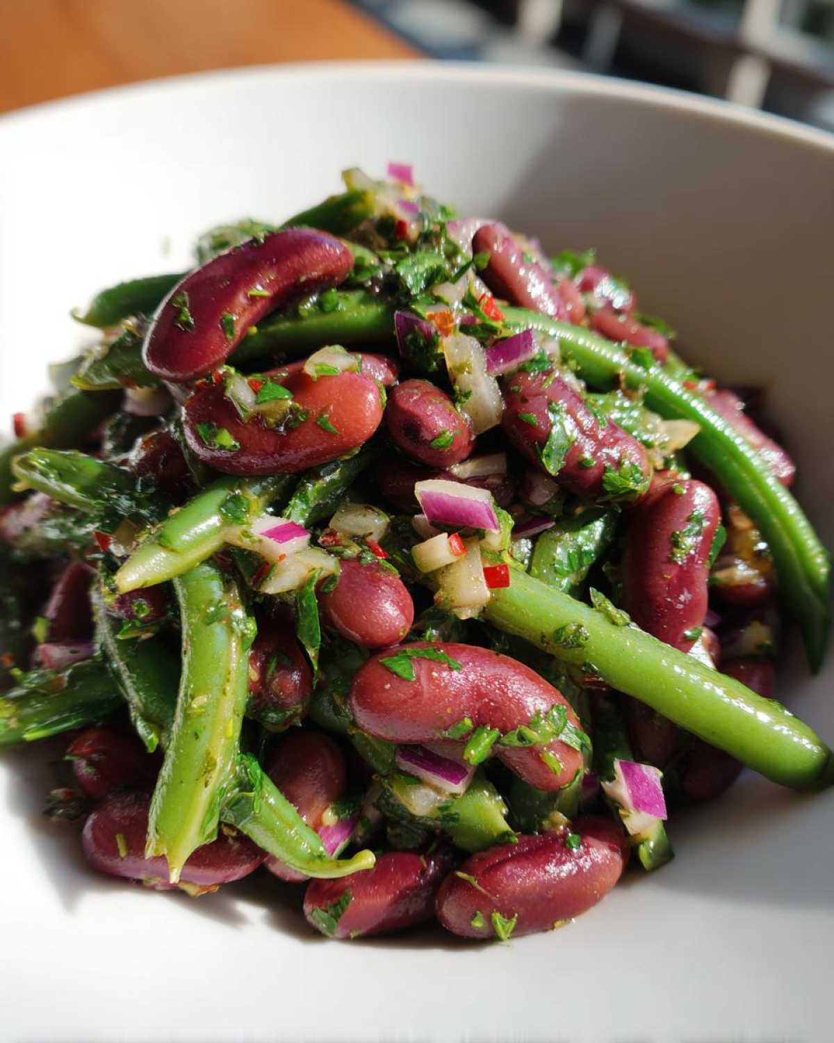 Close-up of a vibrant Bean Salad featuring kidney beans, green beans, red onion, and herbs.