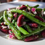 Close-up of a vibrant Bean Salad featuring bright green beans, deep red kidney beans, and chopped red onion.