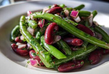 Close-up of a vibrant Bean Salad featuring bright green beans, deep red kidney beans, and chopped red onion.