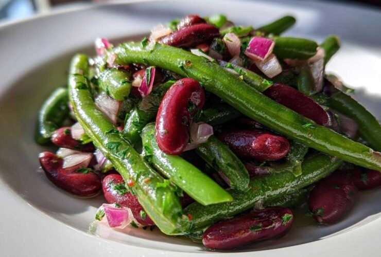 Close-up of a vibrant Bean Salad featuring bright green beans, deep red kidney beans, and chopped red onion.