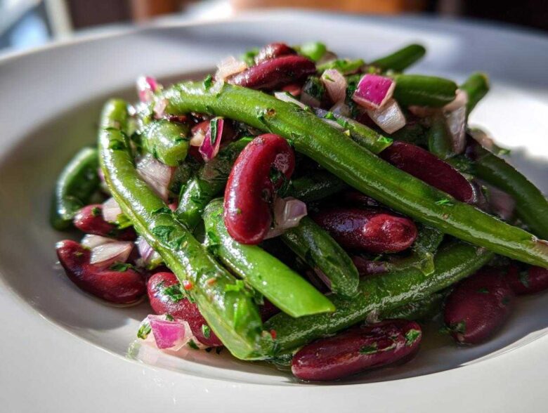 Close-up of a vibrant Bean Salad featuring bright green beans, deep red kidney beans, and chopped red onion.